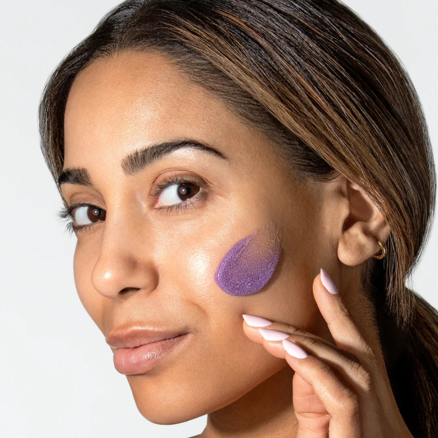 Woman with purple polish applied to cheek, fingers touching face