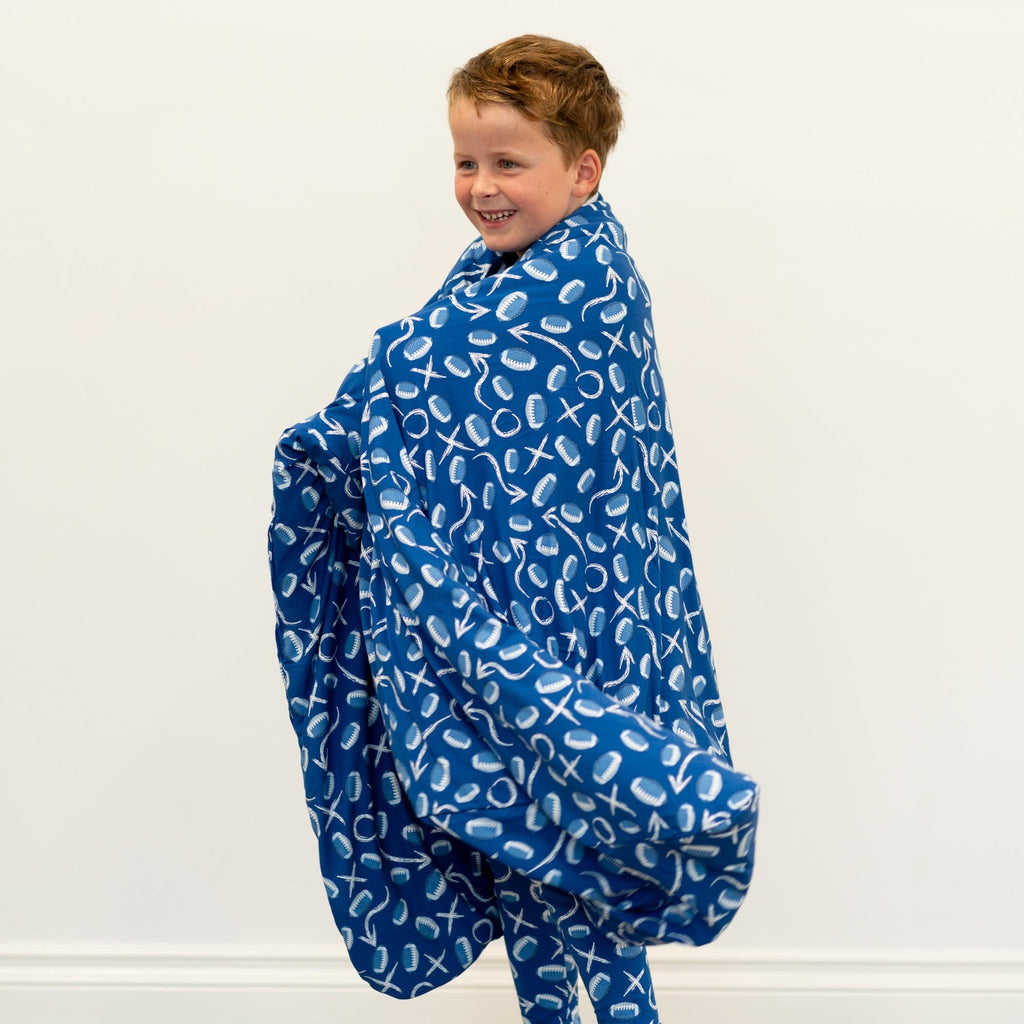 Kids blue patterned blanket wrapped around boy, football-style icons