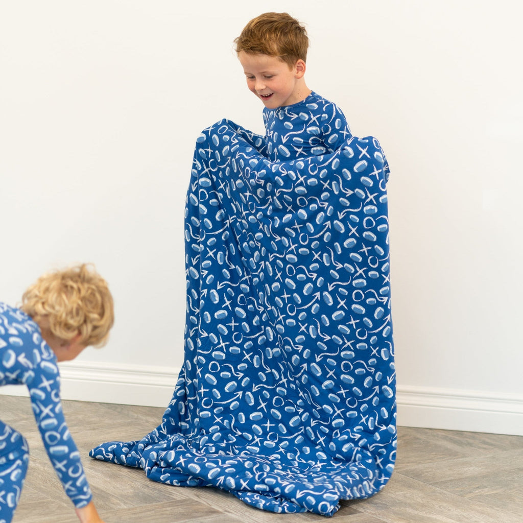 Blue patterned kids blanket spread on floor as boy sits wrapped