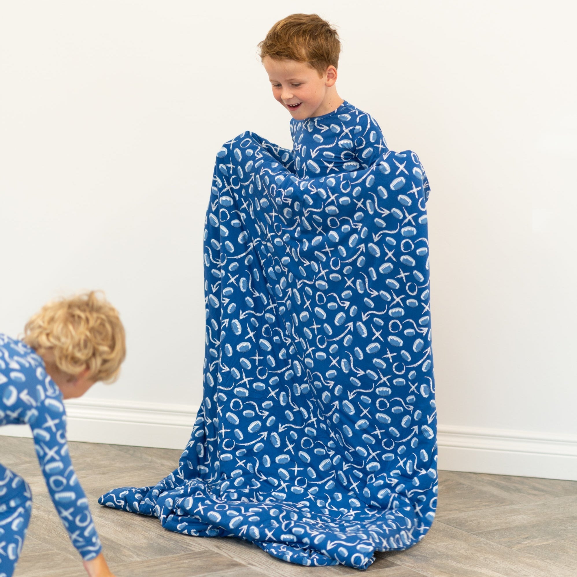 Blue patterned kids blanket spread on floor as boy sits wrapped