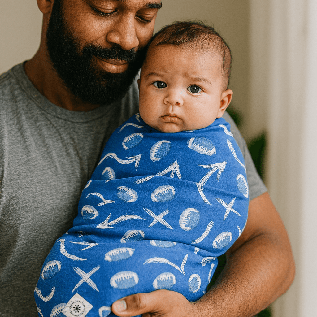 Blue swaddle blanket with white fish and starfish prints, wrapped on baby boy