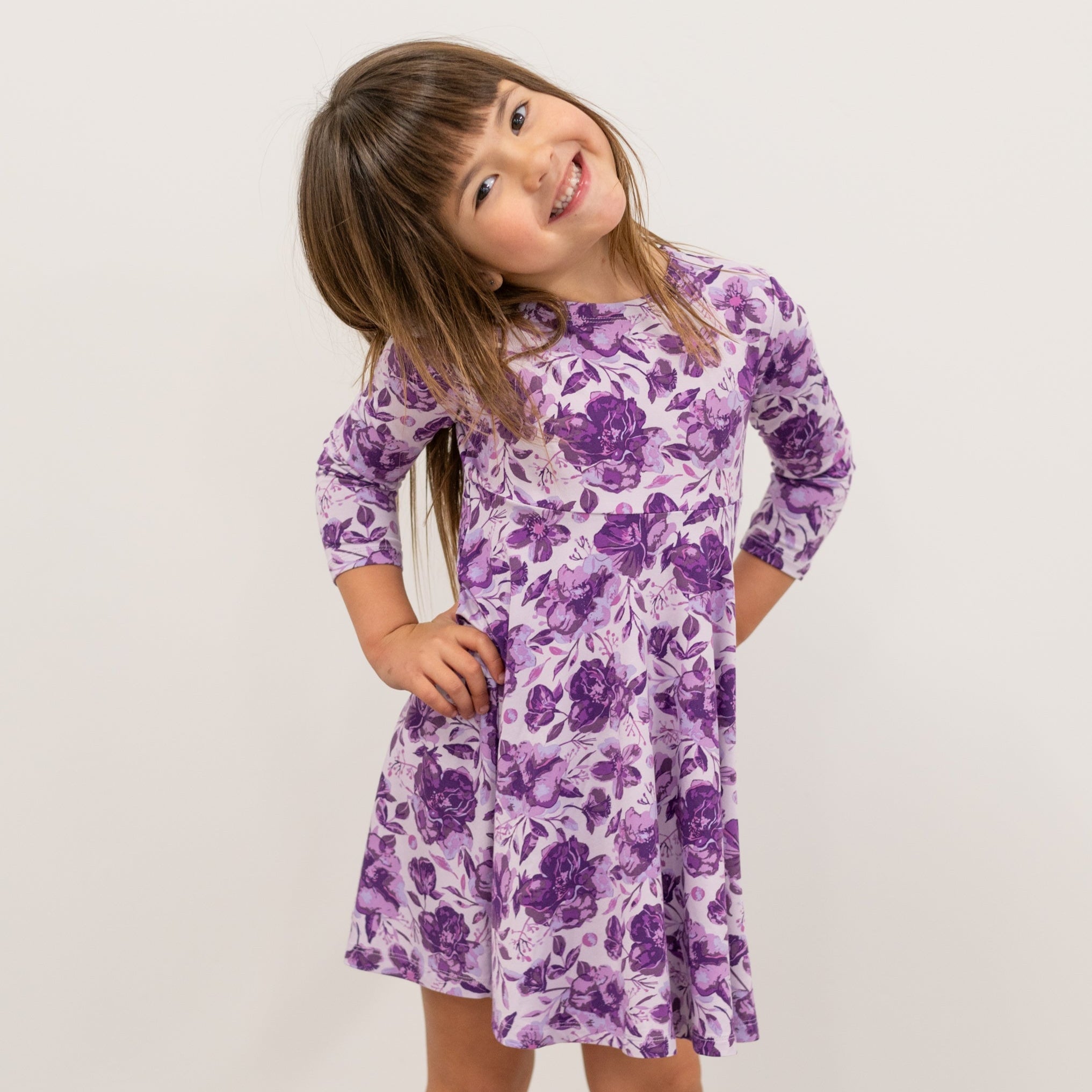 Girls purple floral long-sleeve dress with gathered skirt, standing full-body view