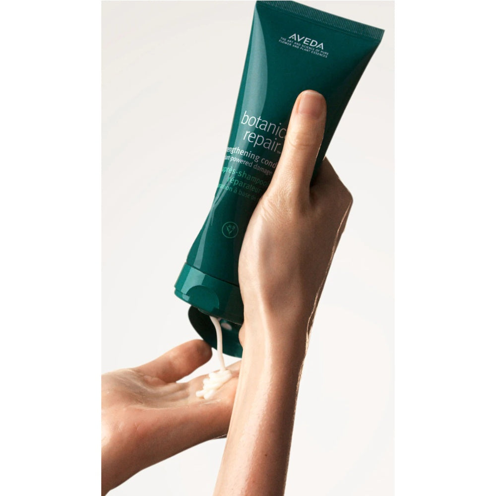 Aveda Botanical Repair conditioner tube being squeezed onto hair by hand