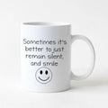 White coffee mug with quote 'Remain silent, and smile' and smiley face icon