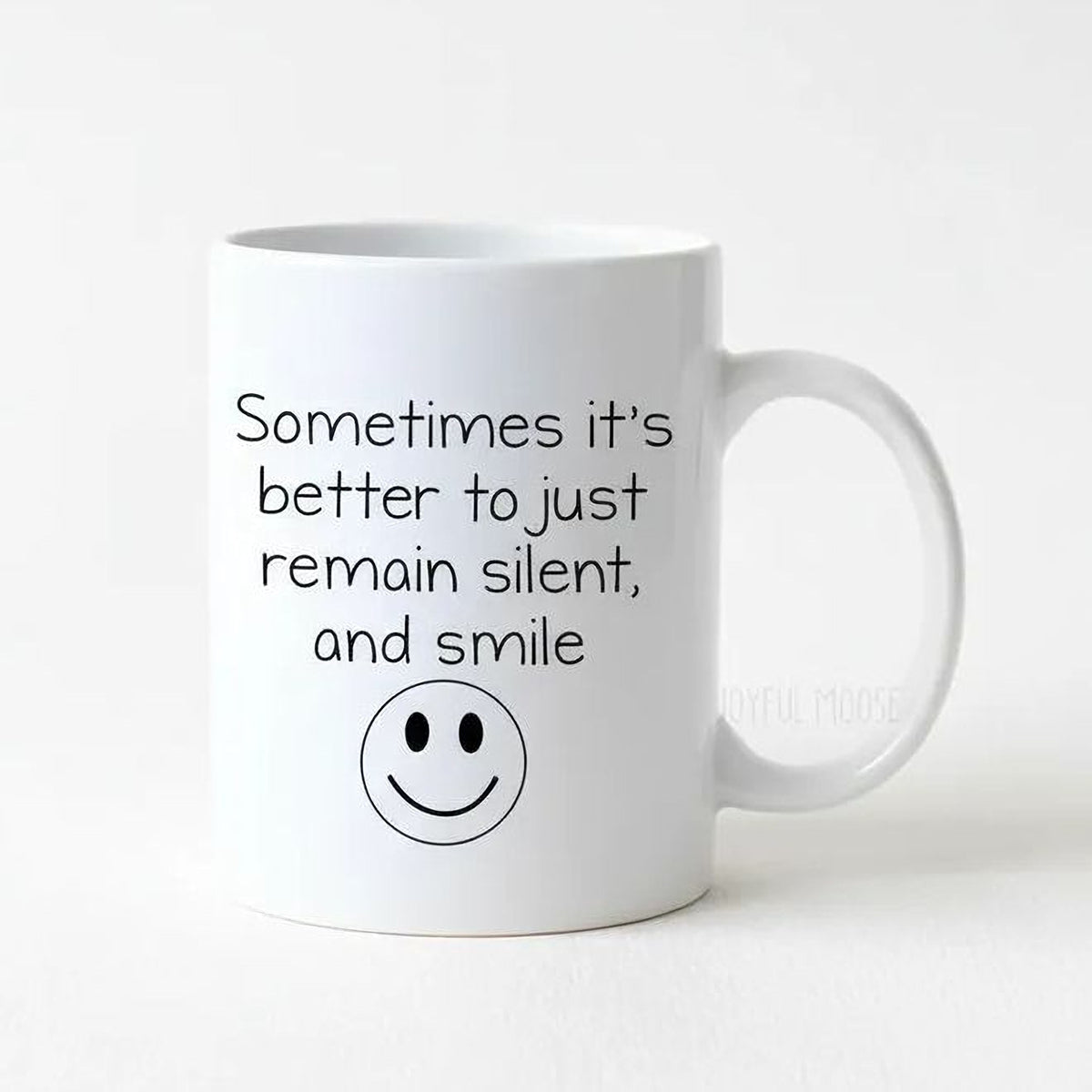 White coffee mug with quote 'Remain silent, and smile' and smiley face icon
