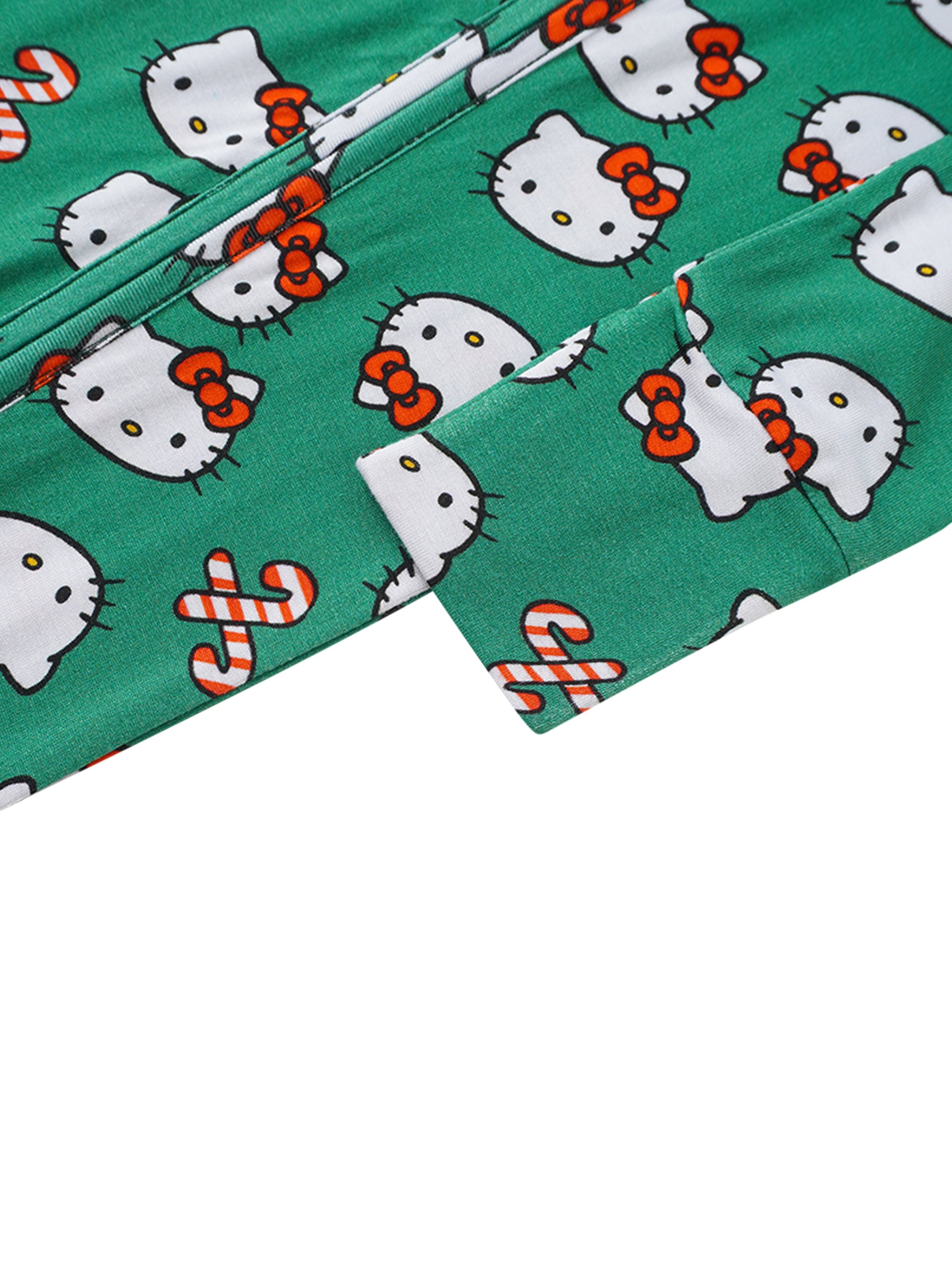 Green baby romper fabric close-up with Hello Kitty faces and candy-cane icons