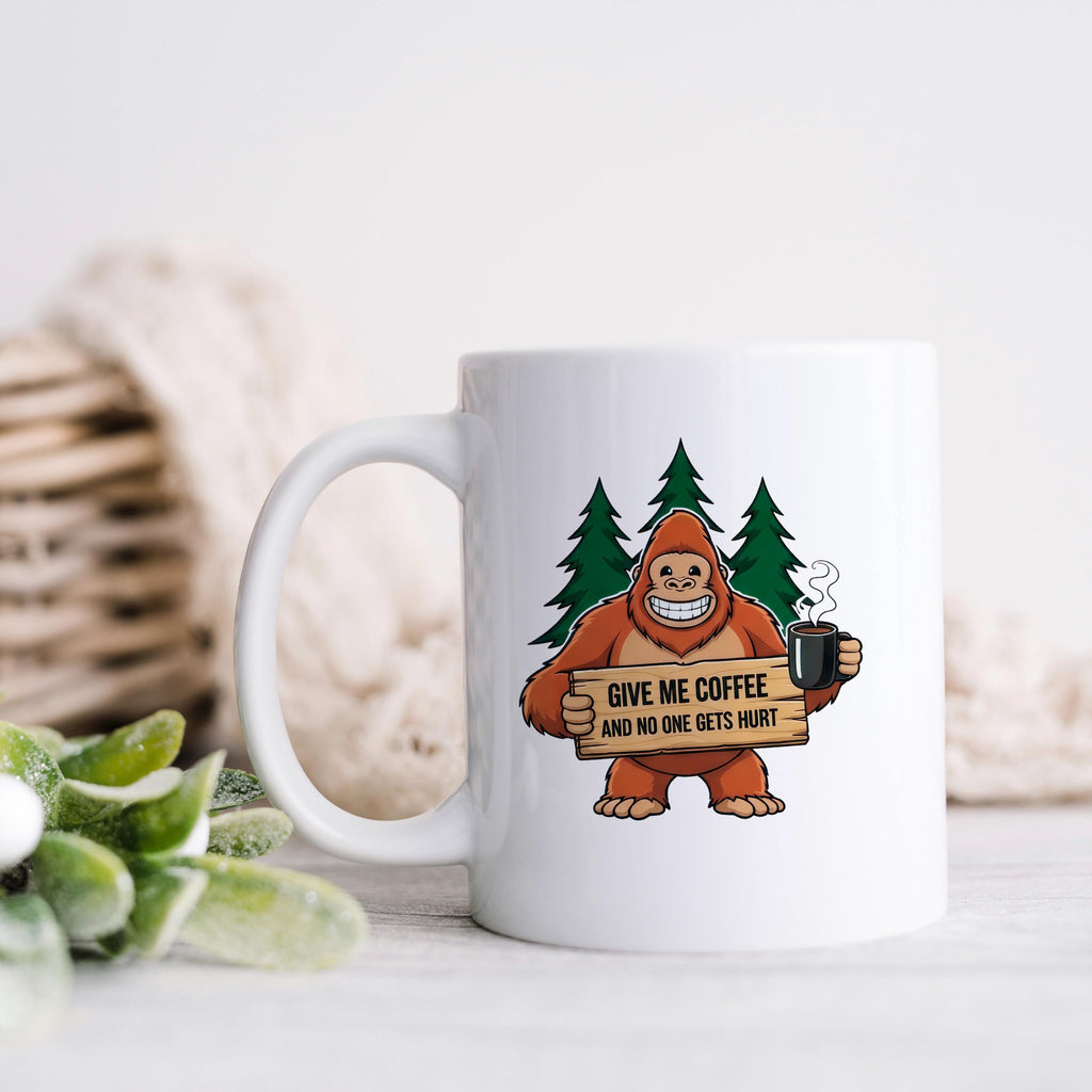 White ceramic coffee mug with Bigfoot graphic holding sign and steaming cup.
