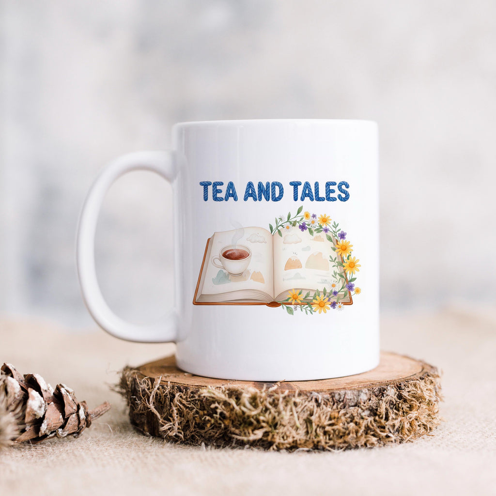 White ceramic mug with "TEA AND TALES" and open book with tea cup illustration