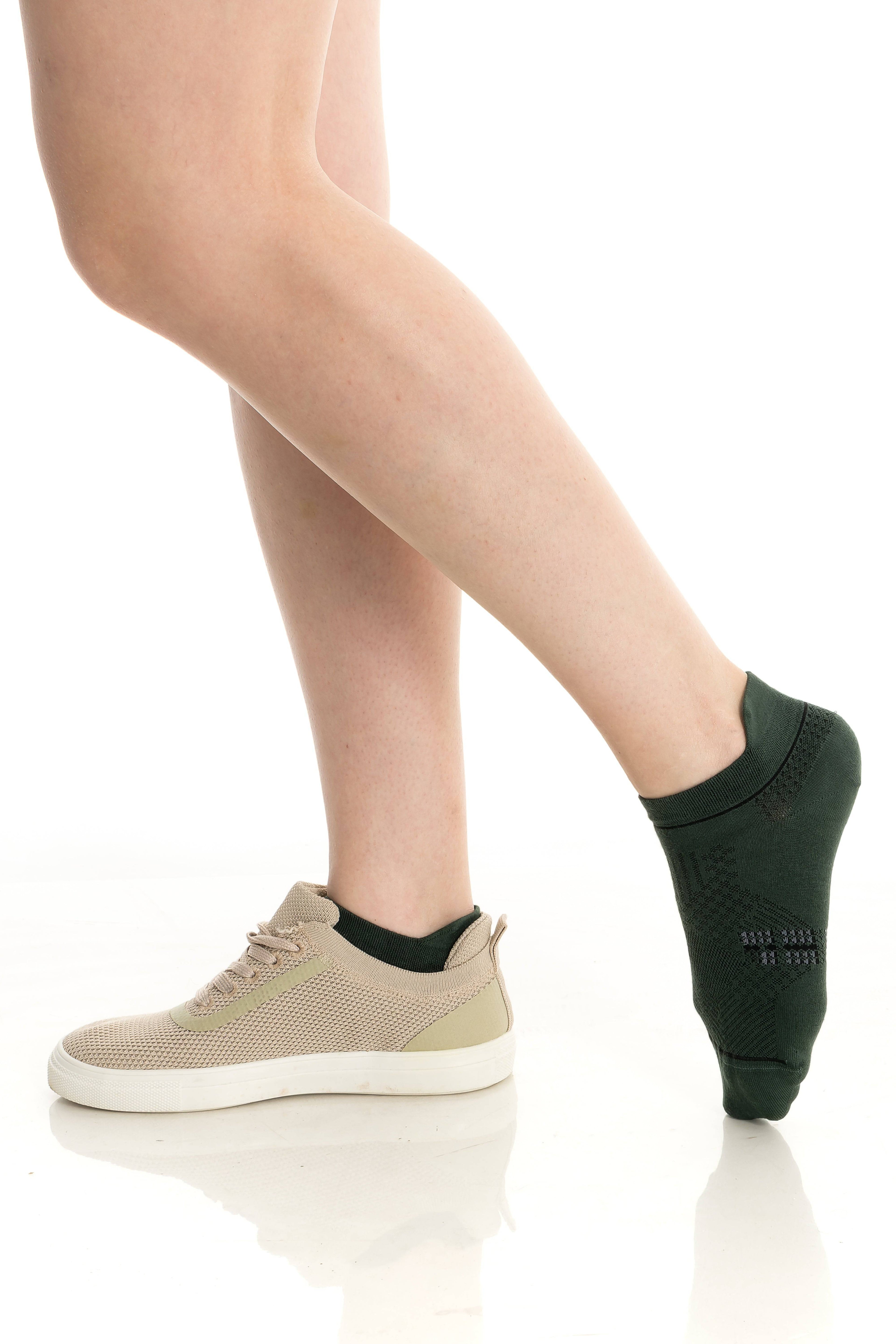 Green ankle socks on feet with sneakers, ribbed cuff and logo detail