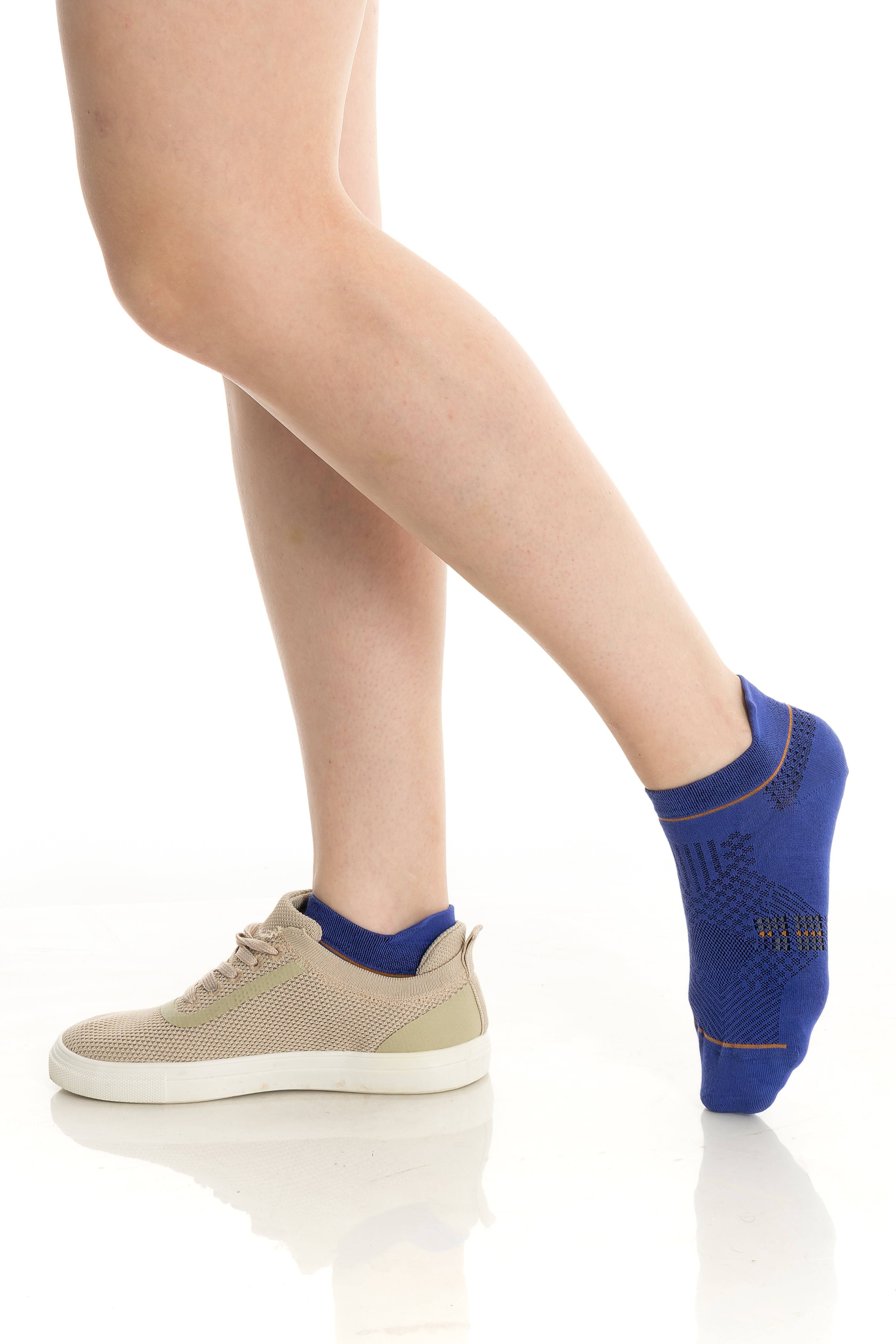 Blue ankle socks on legs with beige sneakers and ribbed orange-trim cuff