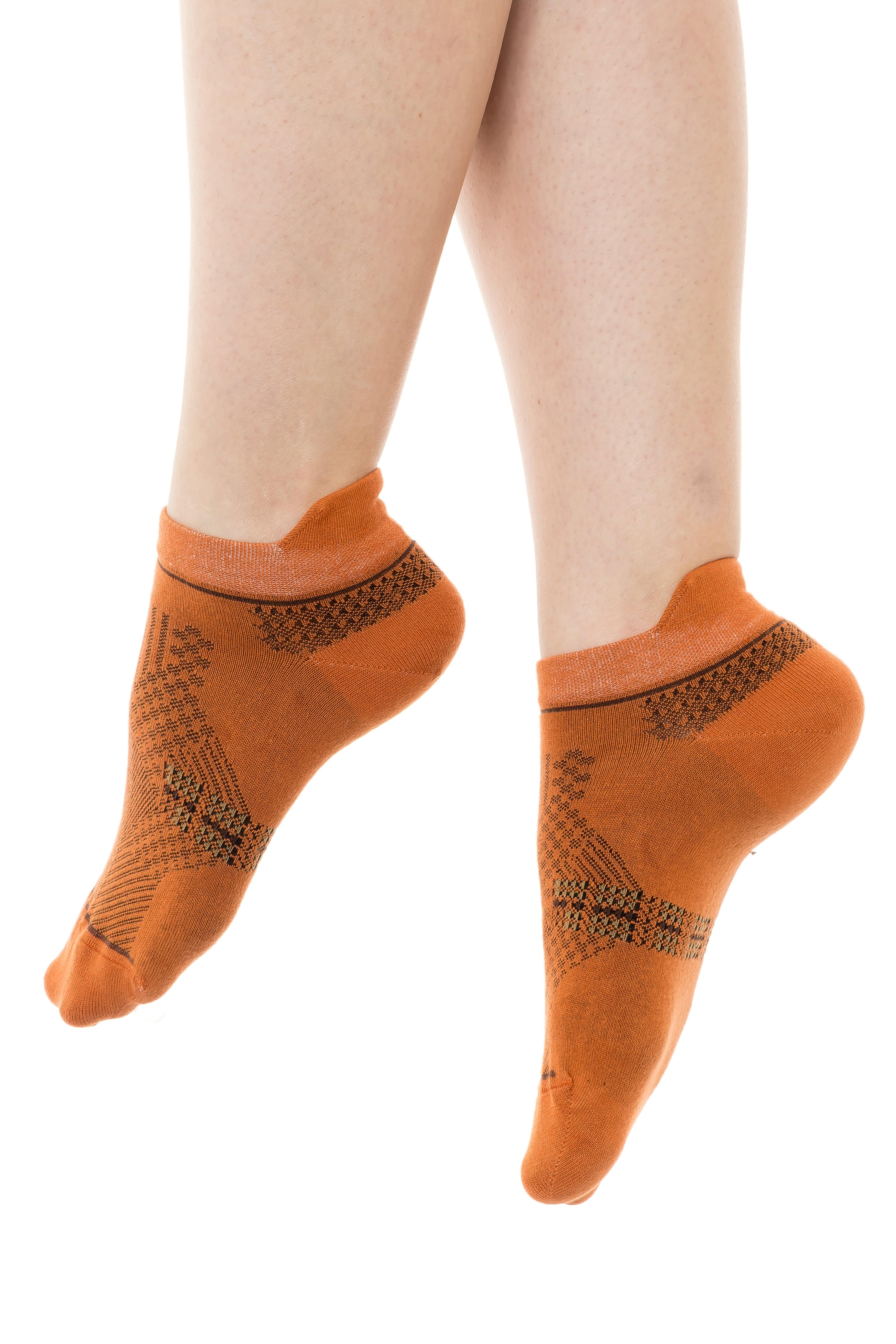 Orange ankle socks with dark geometric knit pattern on both feet