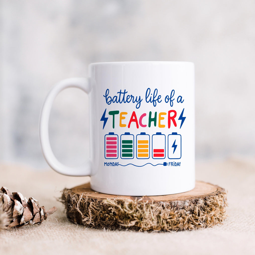 White ceramic mug with “battery life of a TEACHER” battery graphic on wood slice