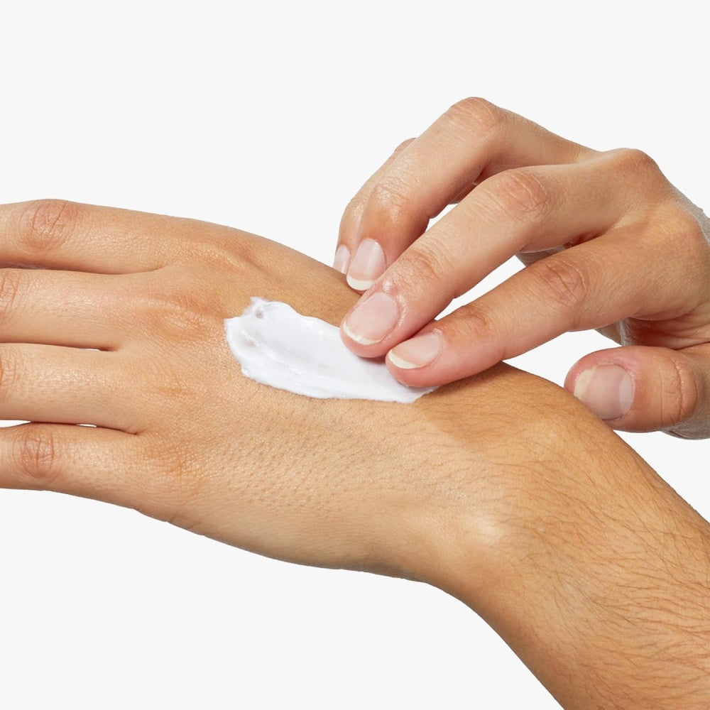 White body cream spread on forearm by two hands