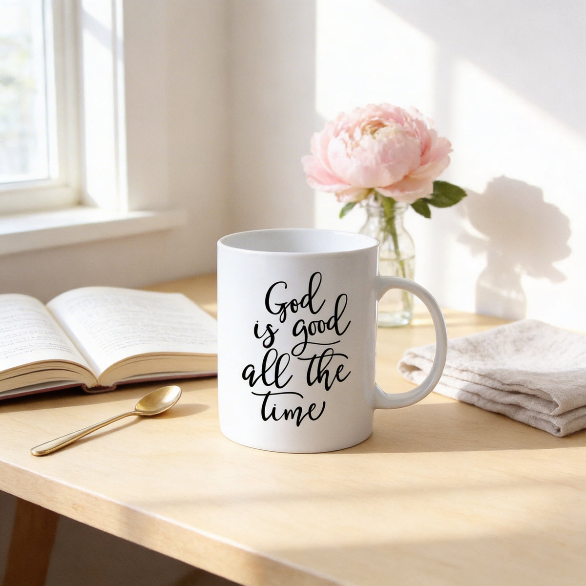 White ceramic coffee mug with 'God is good all the time' script, side view