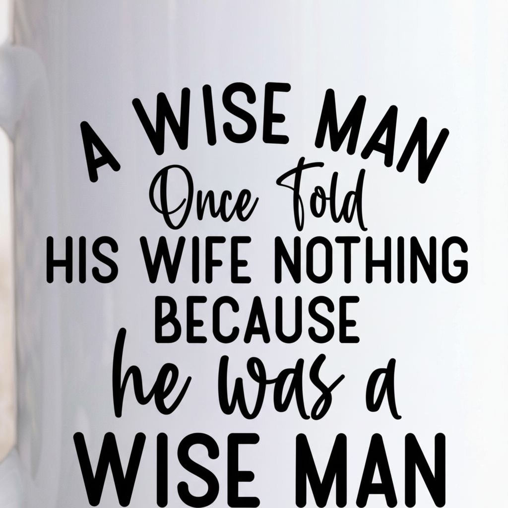 Close-up white ceramic coffee mug showing "A WISE MAN" quote text