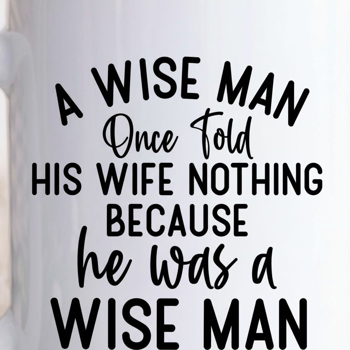 Close-up white ceramic coffee mug showing "A WISE MAN" quote text