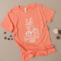 Coral graphic bicycle quote T-shirt with white “Life is a beautiful ride” print