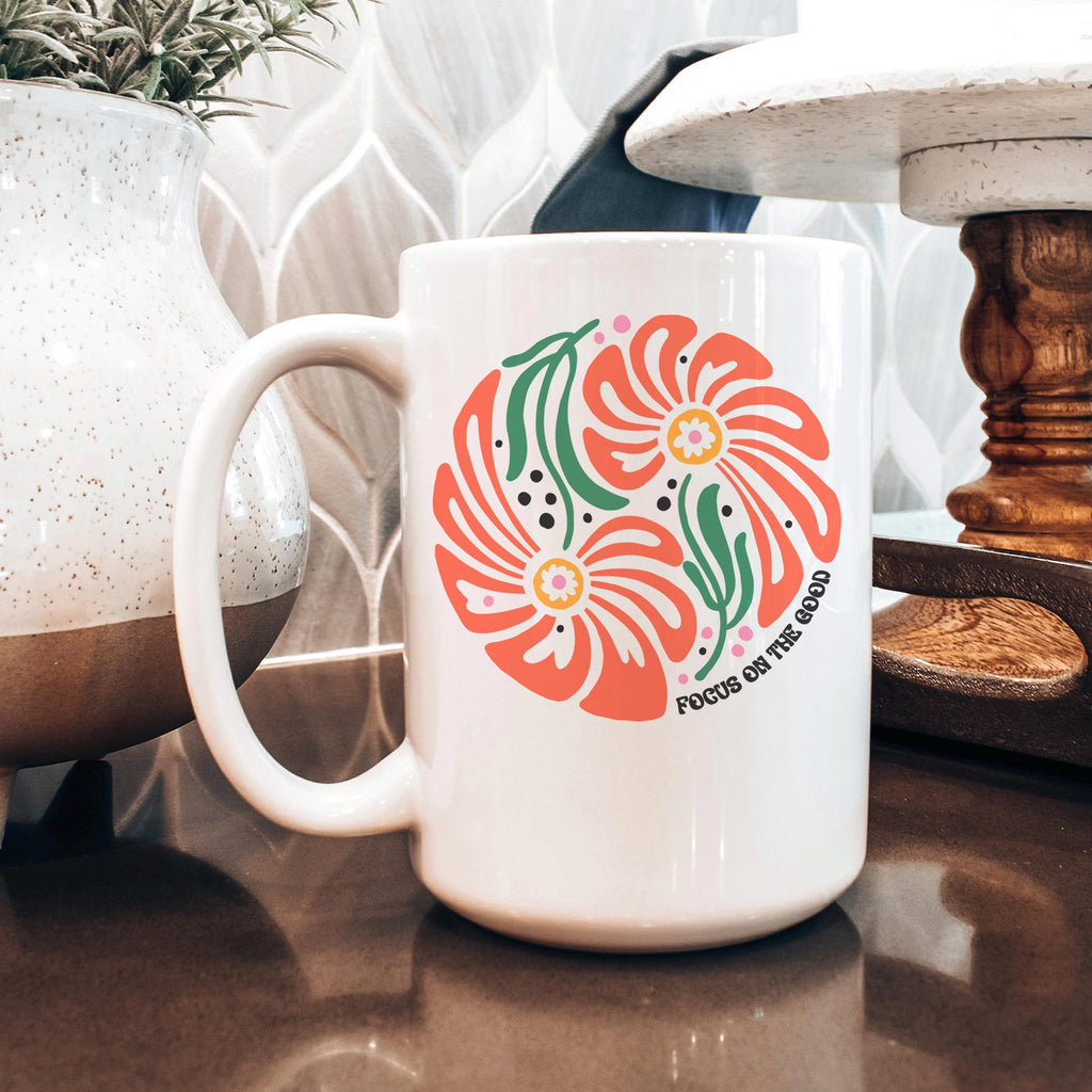 White ceramic mug with coral floral design and green leaves on a countertop