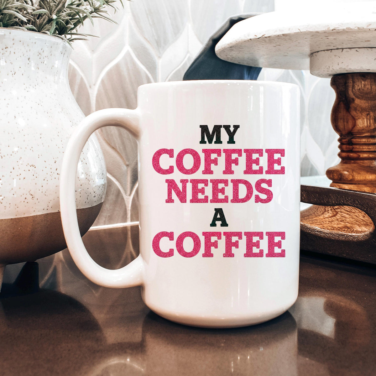 White ceramic mug featuring "MY COFFEE NEEDS A COFFEE" pink and black lettering