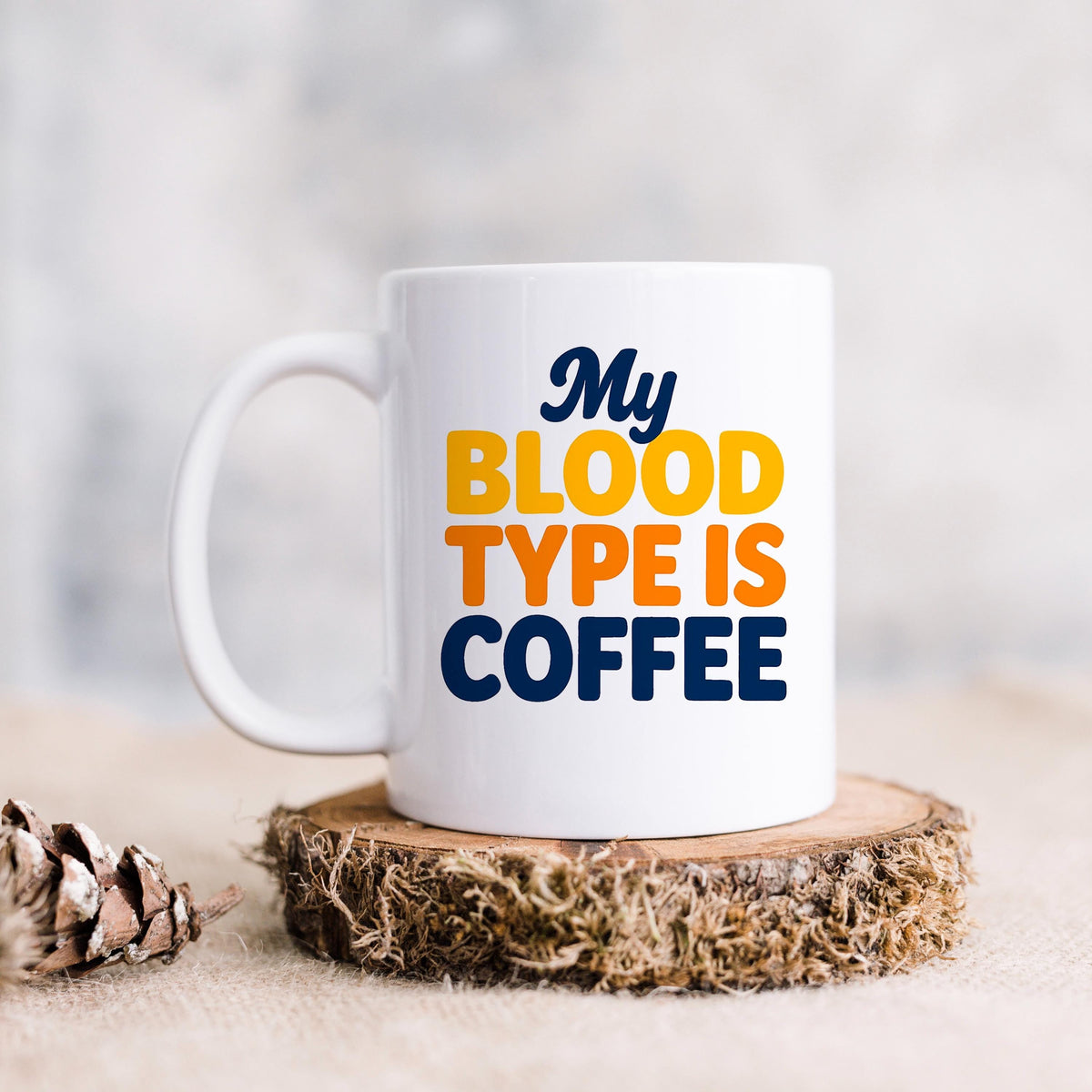 White ceramic coffee mug with handle, “My BLOOD TYPE IS COFFEE” printed in color.