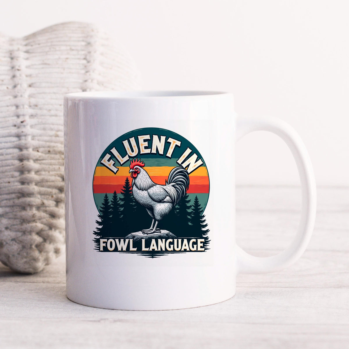 White ceramic coffee mug with rooster logo and “FLUENT IN FOWL LANGUAGE” text