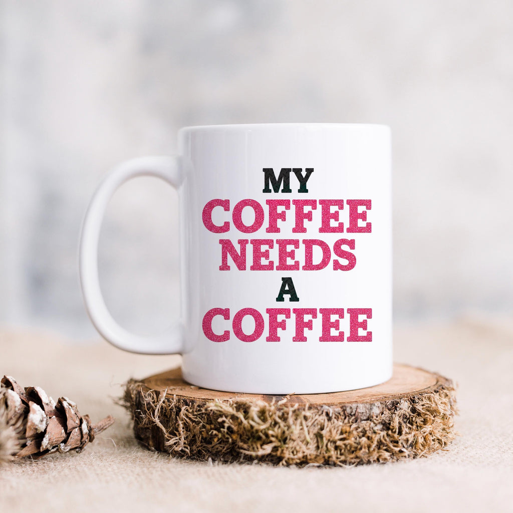 White ceramic coffee mug with "MY COFFEE NEEDS A COFFEE" slogan in pink and black