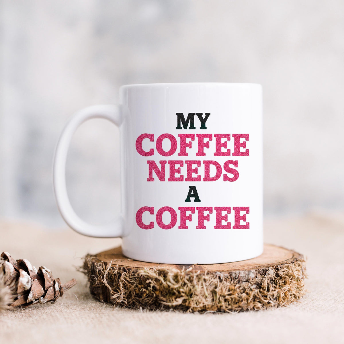 White ceramic coffee mug with "MY COFFEE NEEDS A COFFEE" slogan in pink and black