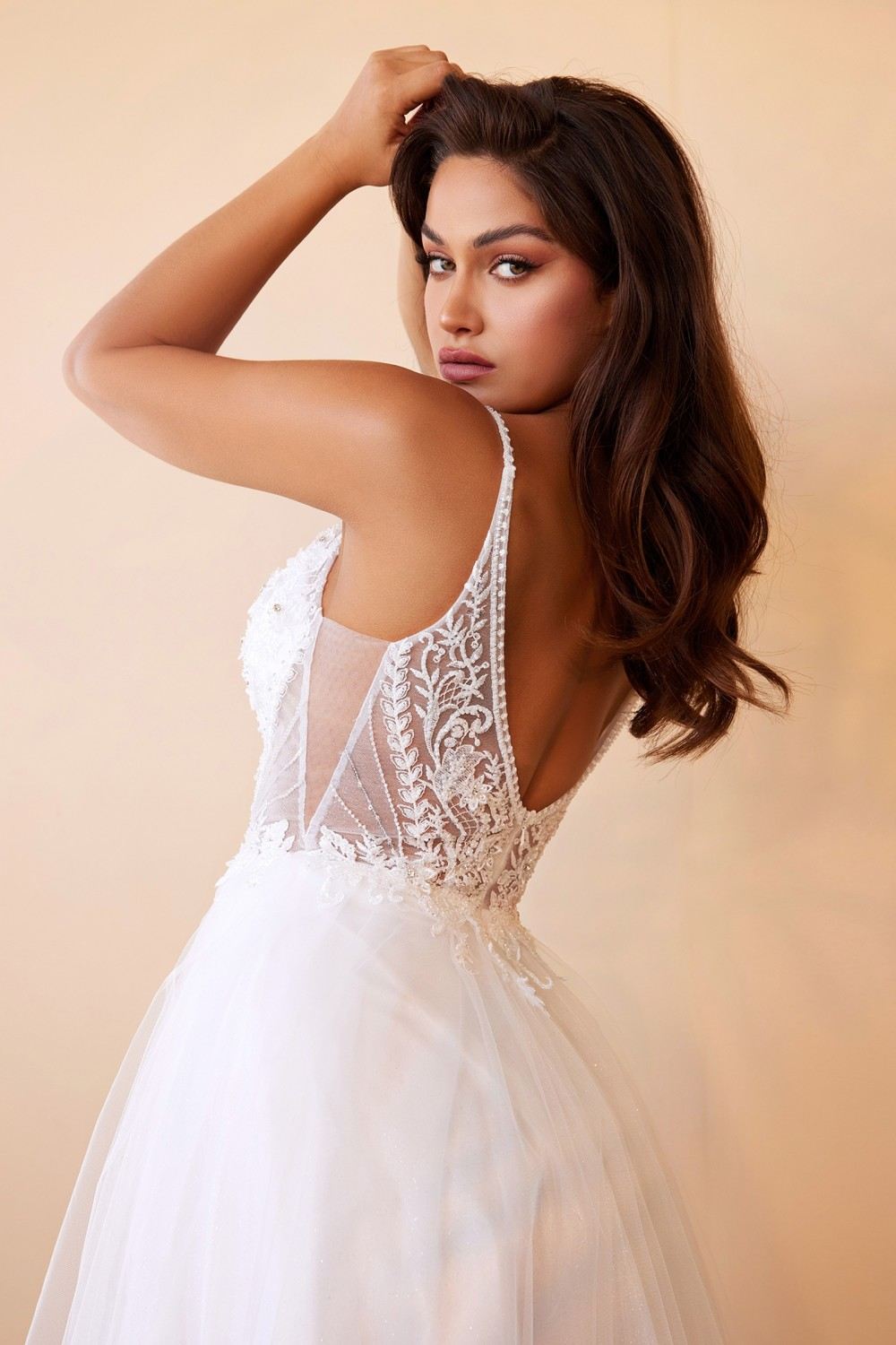 Off-white bridal gown with sheer lace back, spaghetti straps, and layered tulle skirt