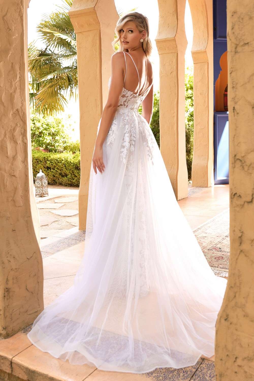 Off-white lace wedding gown with sheer overlay, sleeveless bodice, flowing A-line skirt