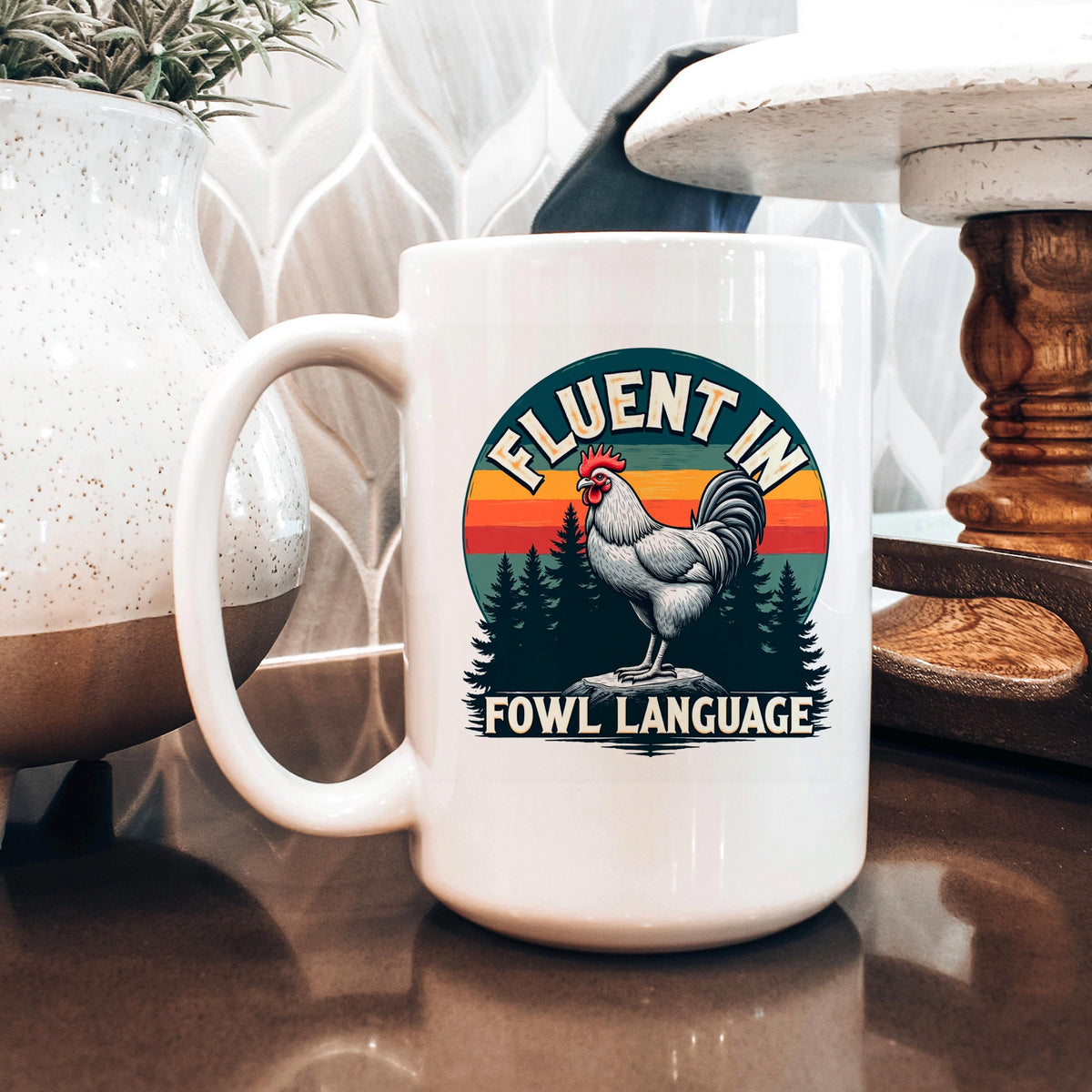 White ceramic coffee mug with rooster logo and “FLUENT IN FOWL LANGUAGE” text