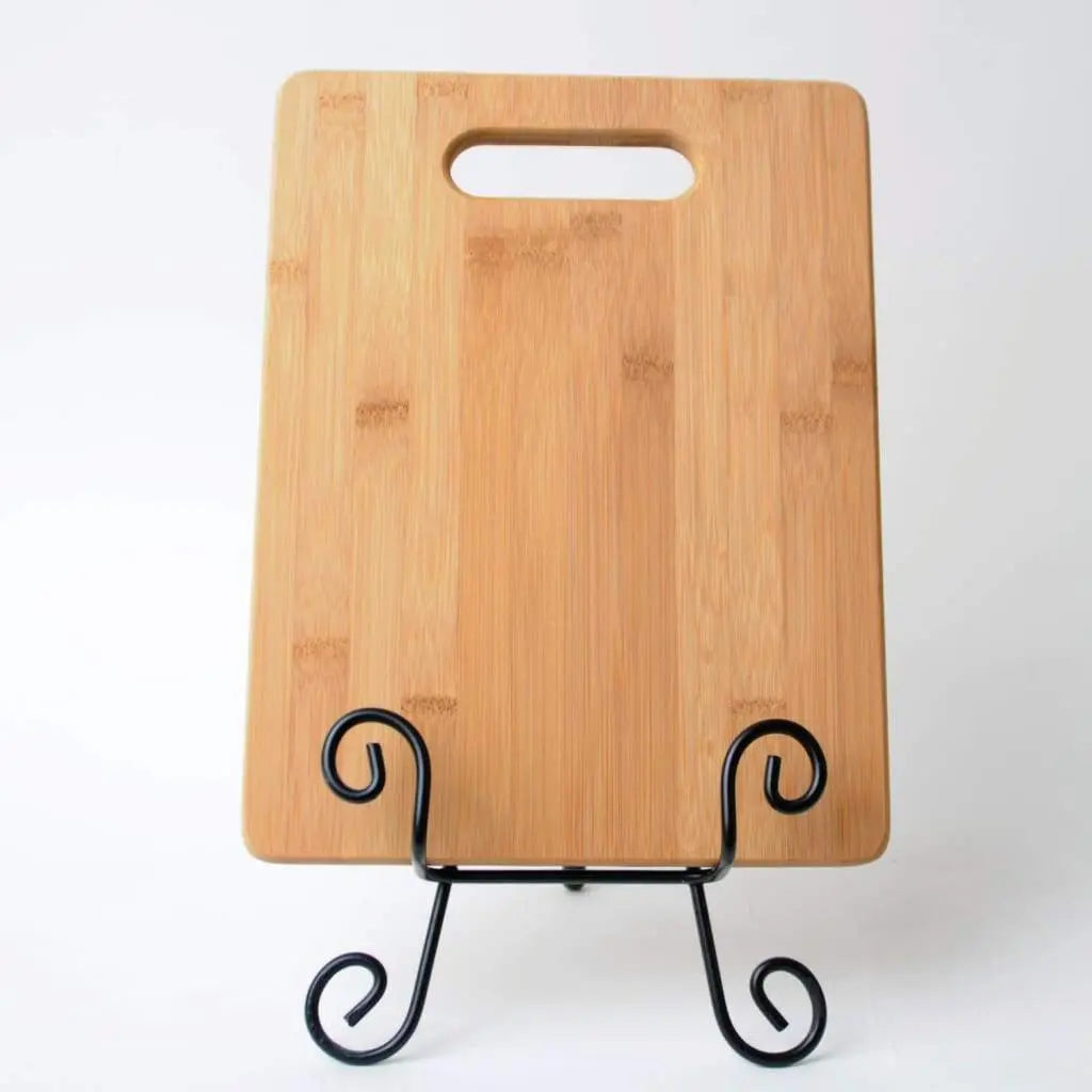 Bamboo cutting board with oval handle, displayed on a black tabletop stand