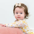 Infant floral long-sleeve romper in pastel yellow, pink, and white; worn with headband bow