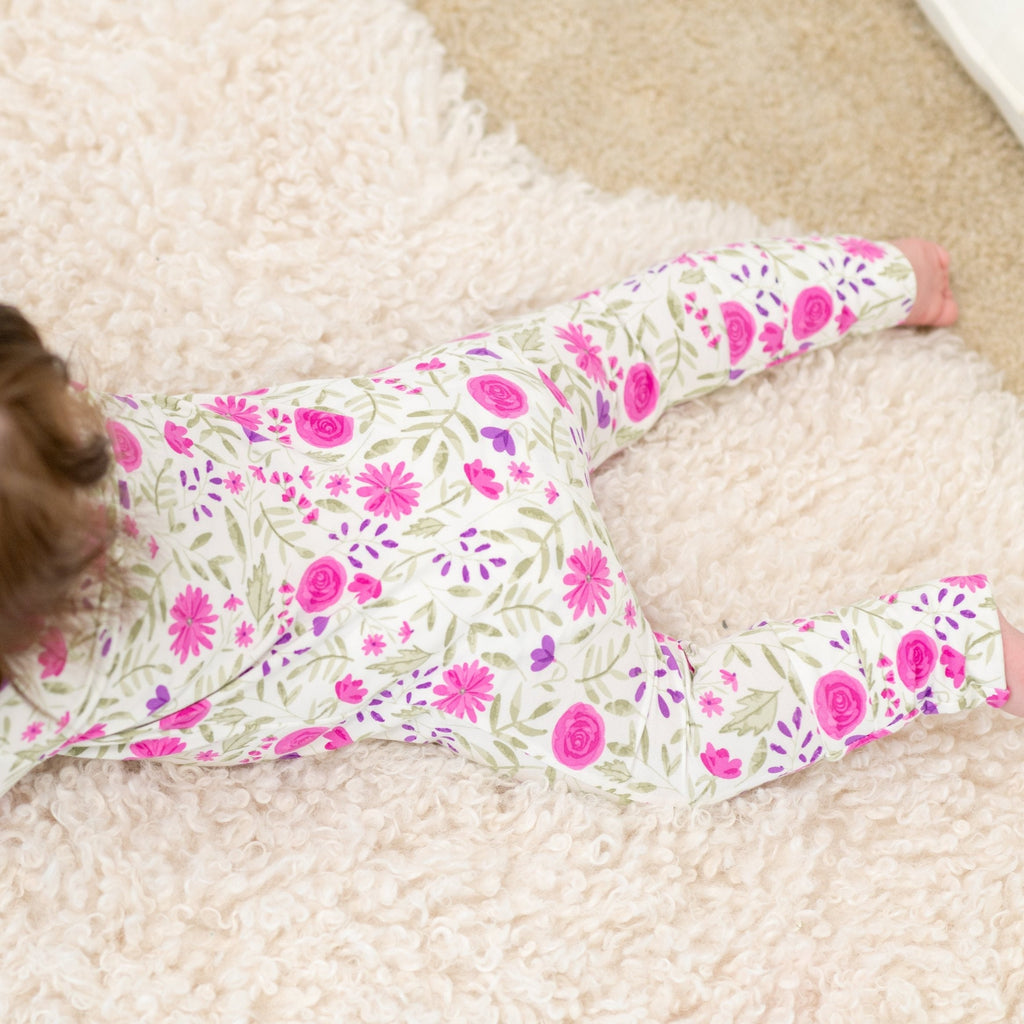 Floral baby romper close-up with pink and purple flowers on white fabric