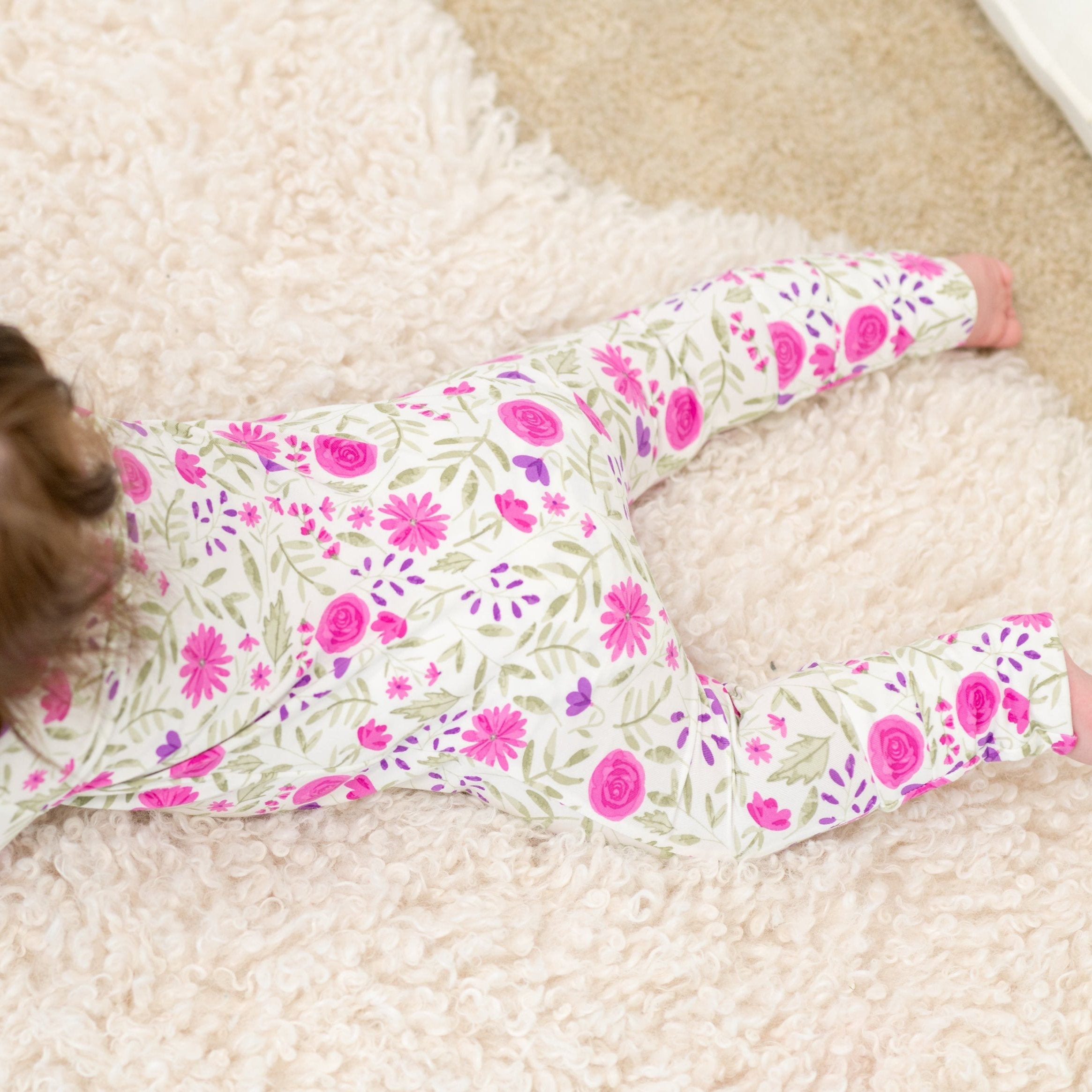 Floral baby romper close-up with pink and purple flowers on white fabric