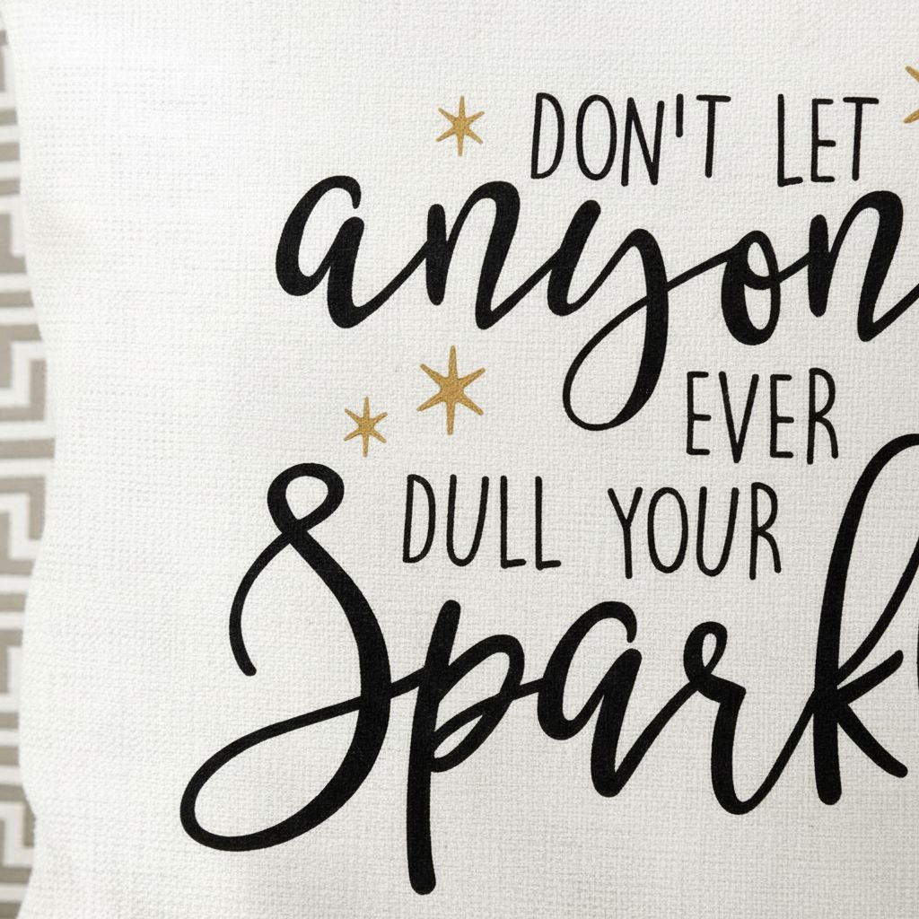 Close-up of white pillow cover text: 'Don't let anyone ever dull your sparkle' in black