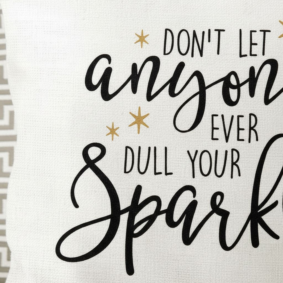 Close-up of white pillow cover text: 'Don't let anyone ever dull your sparkle' in black