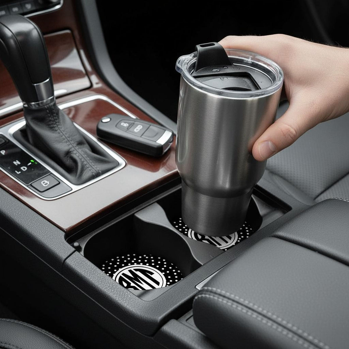 Black polka-dot car cup holder insert with RM monogram, holding a travel mug