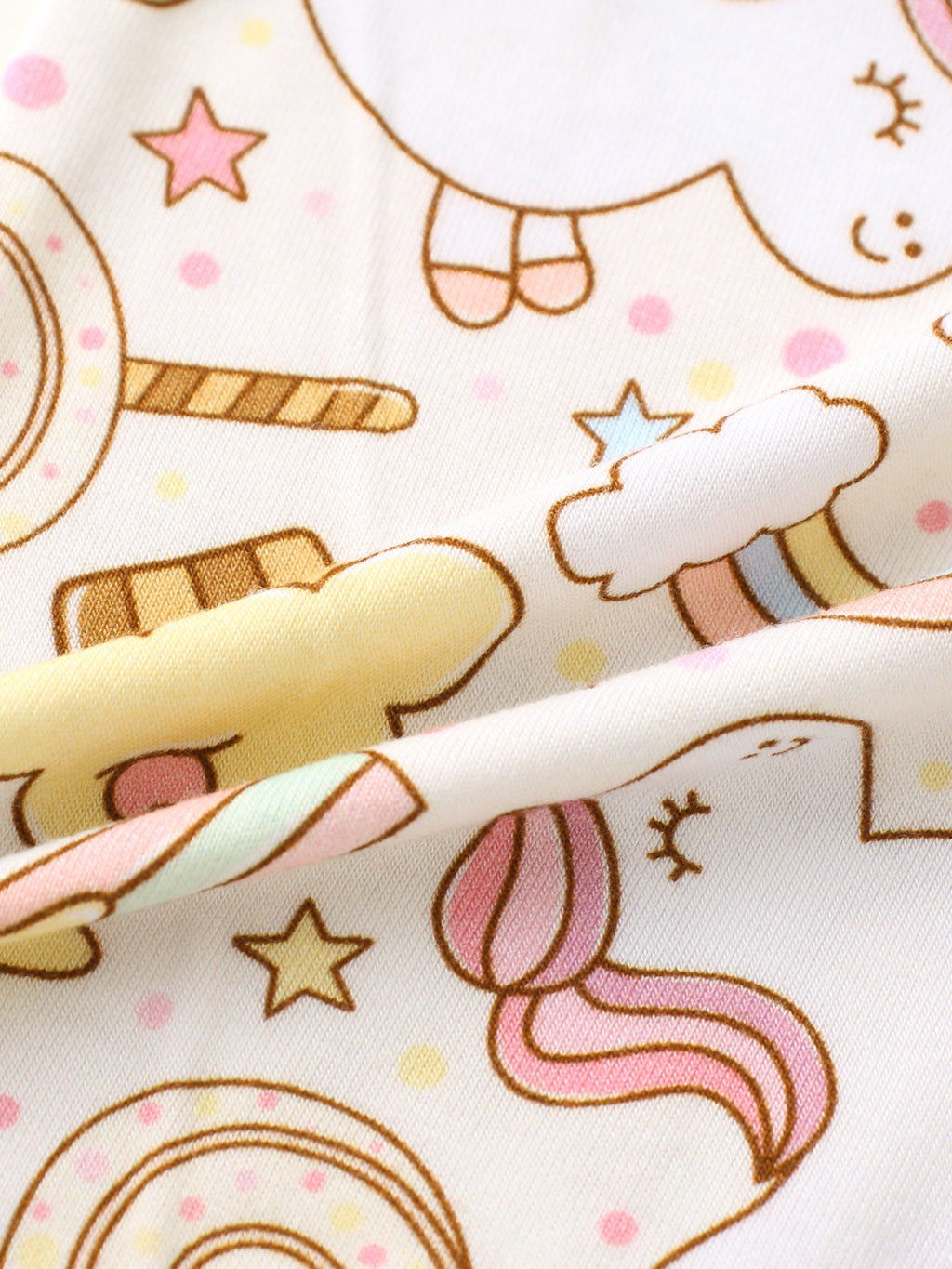 Close-up of rainbow snacks print fabric on a cream-cuffed baby romper sleeve