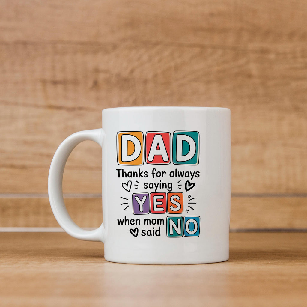 White ceramic mug with “DAD” and “YES/NO” joke graphic on the front