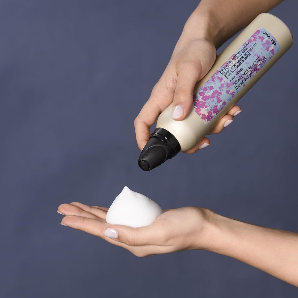 Curl moisturizing mousse bottle in hand dispensing white foam