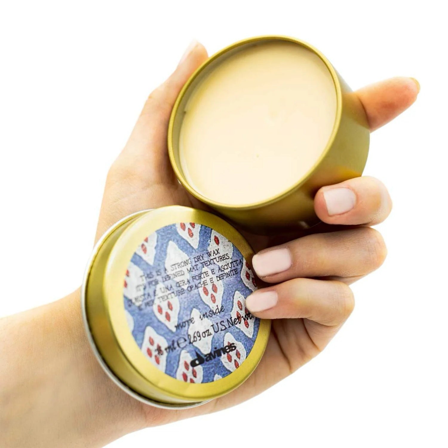 Davines dry wax tin with open lid held in hands, showing cream wax inside