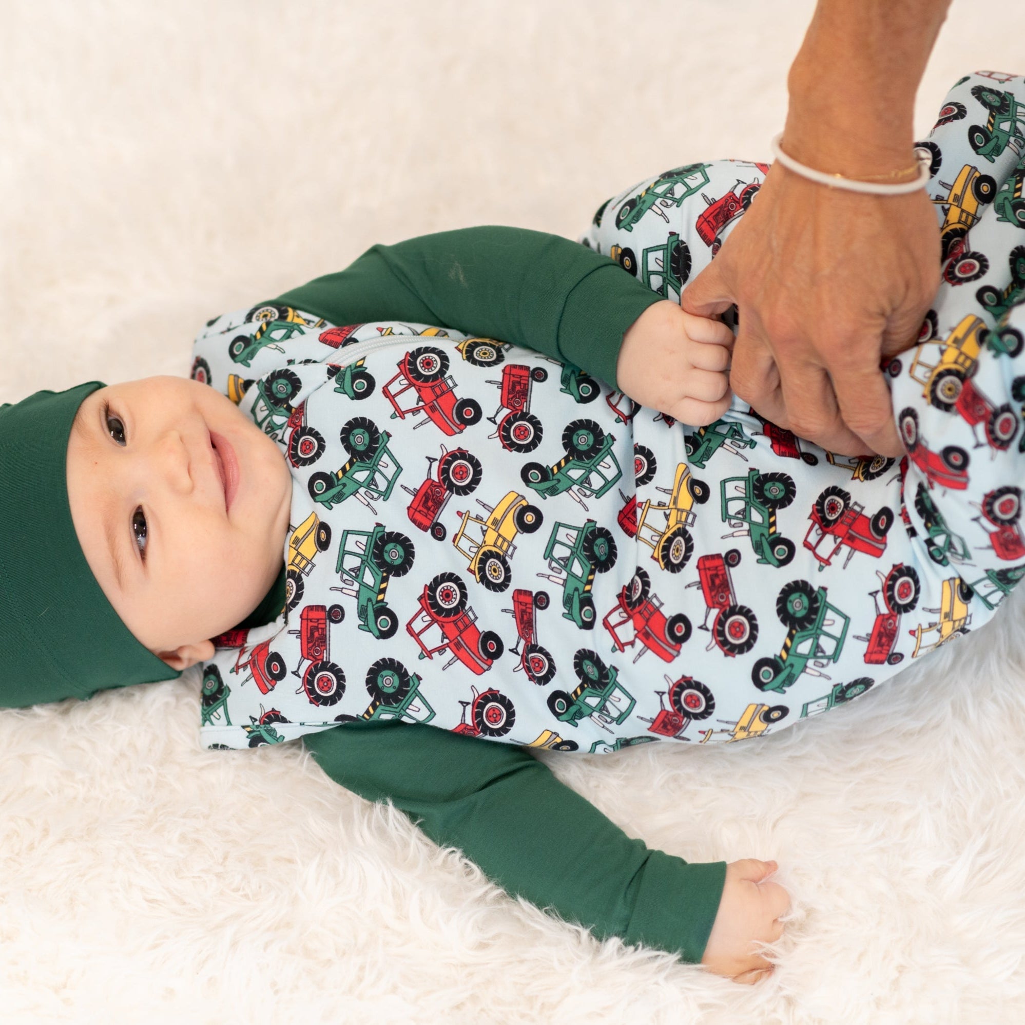 Down On the Farm sleep sack with tractor print and green sleeves, worn on baby