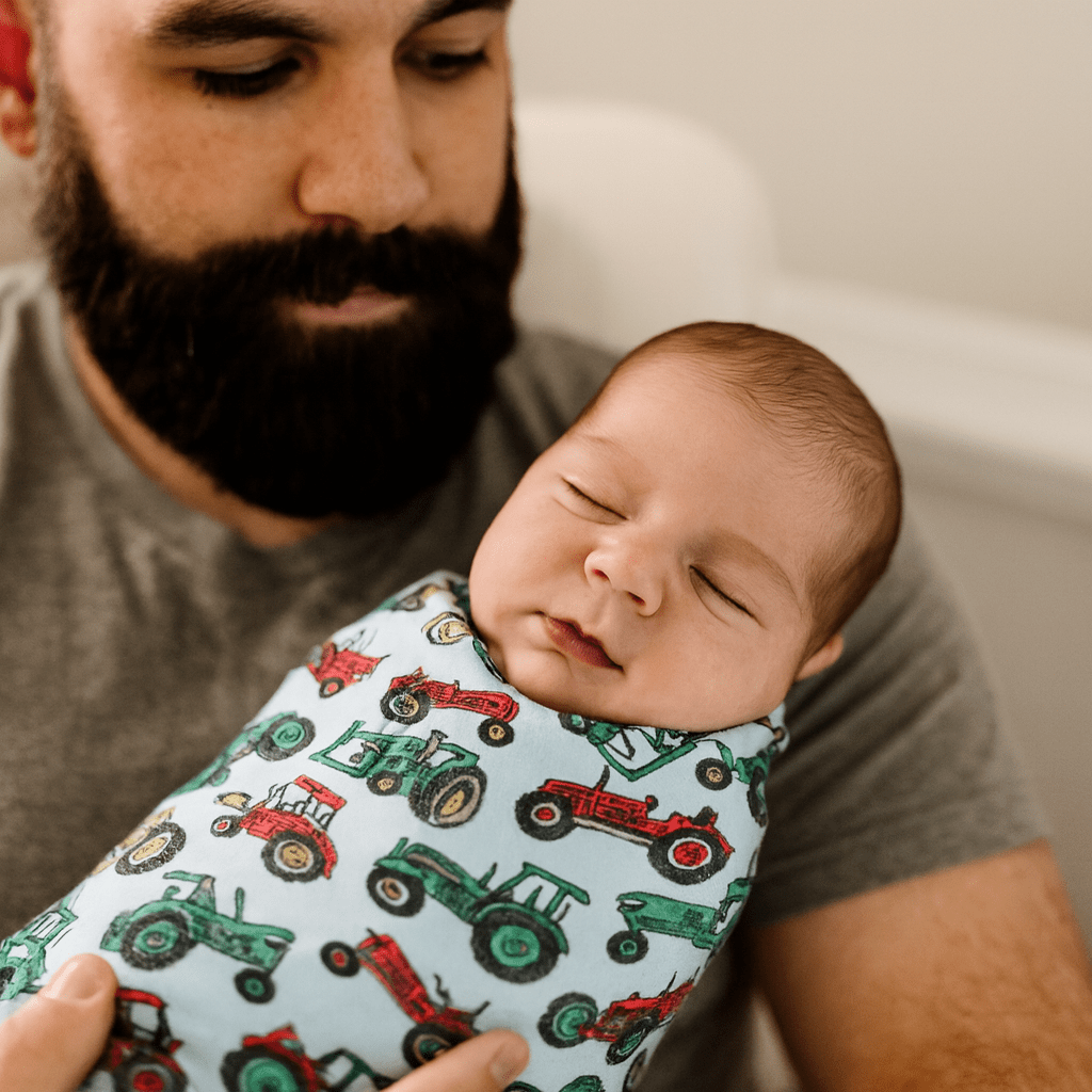 Farm tractor printed baby swaddle blanket, wrapped around an infant