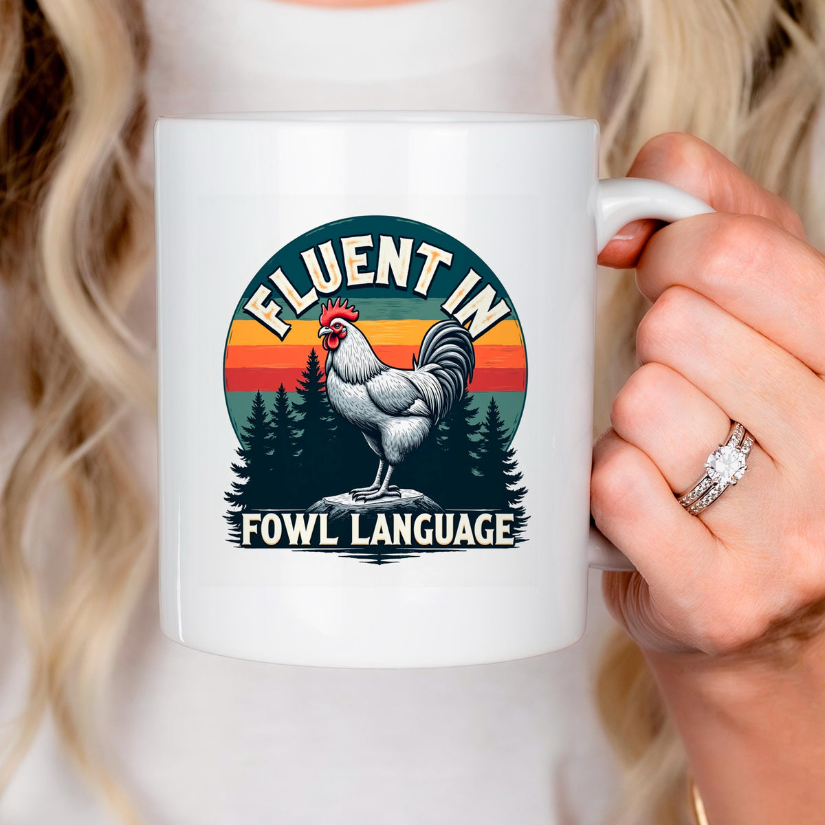 White ceramic mug close-up with rooster graphic and “FLUENT IN FOWL LANGUAGE” text