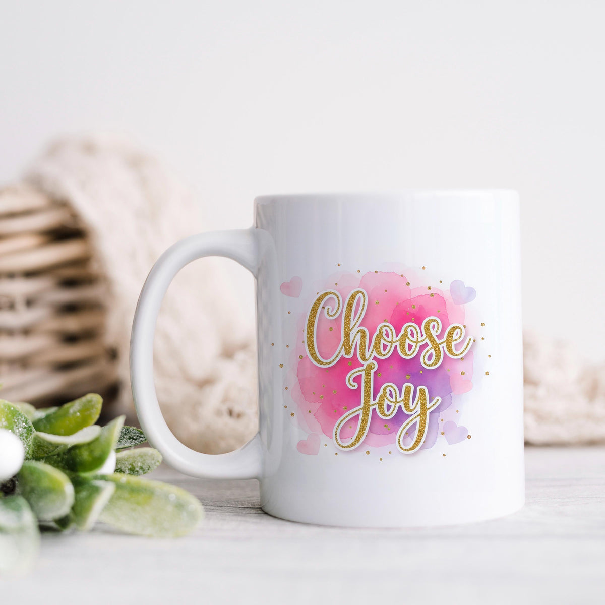 White ceramic coffee mug with pink watercolor "Choose Joy" lettering and handle