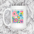 White ceramic coffee mug with colorful floral print and “Sunshine State of Mind”.