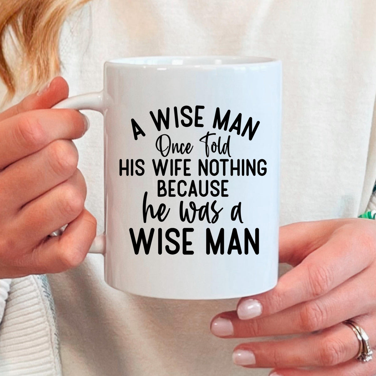 White ceramic coffee mug with "A WISE MAN" quote, held by two hands