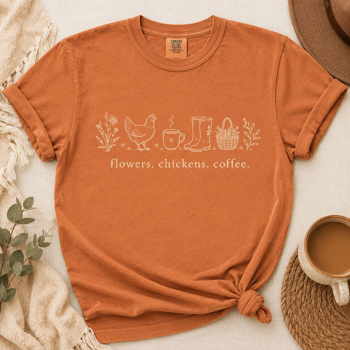 Rust orange unisex t-shirt with chicken, coffee, and flowers graphic; knotted front hem