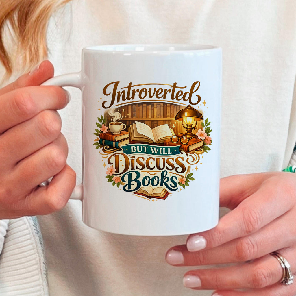 White ceramic mug held in hands, with colorful "Introverted, but will discuss books" quote