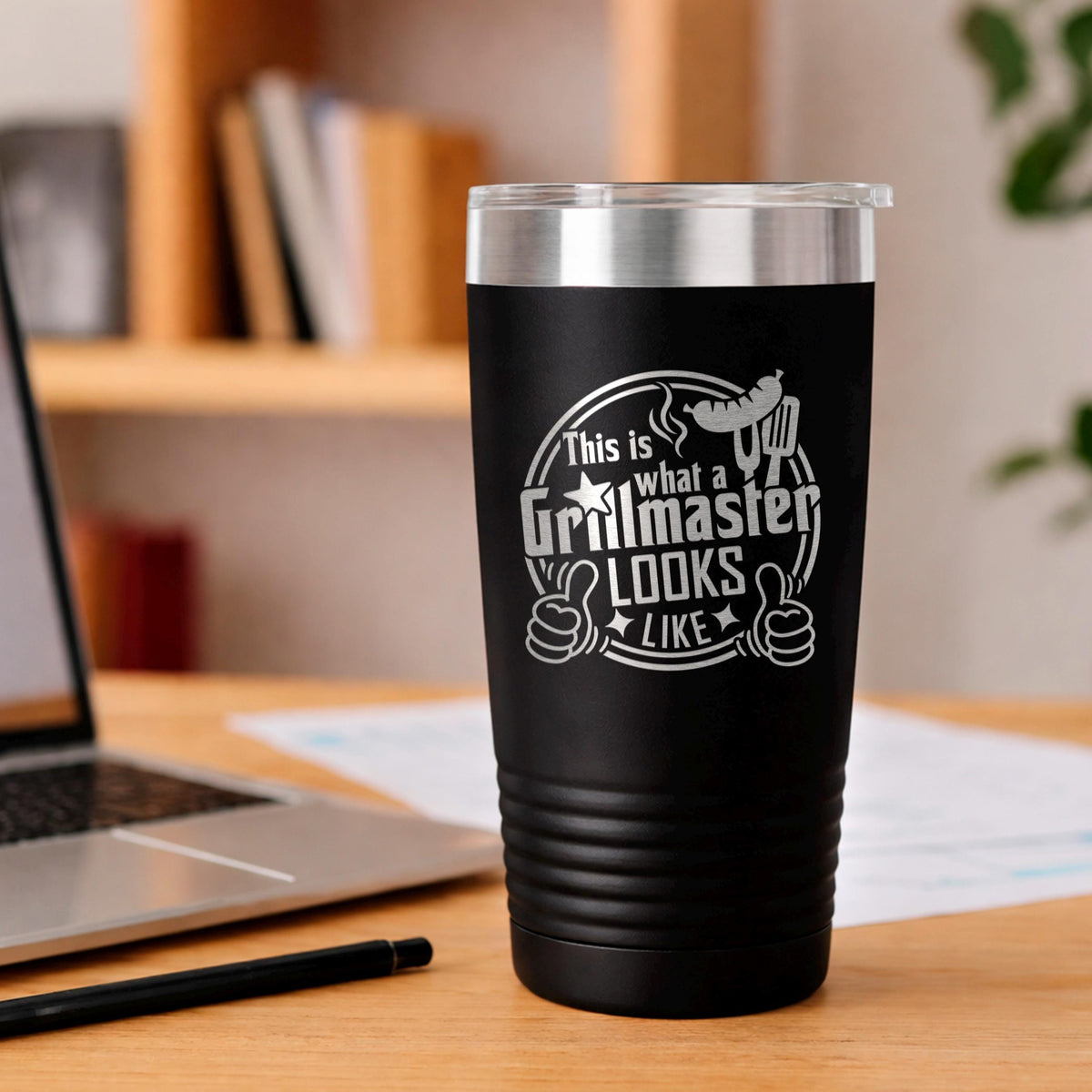 Black insulated stainless steel tumbler on wooden table with Grillmaster logo